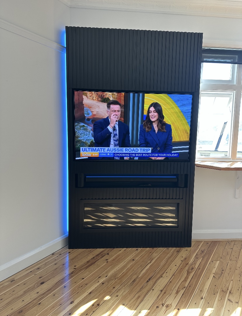 Black fluted timber feature wall with mounted TV, fireplace and LED accent lighting by Mr Woodworx