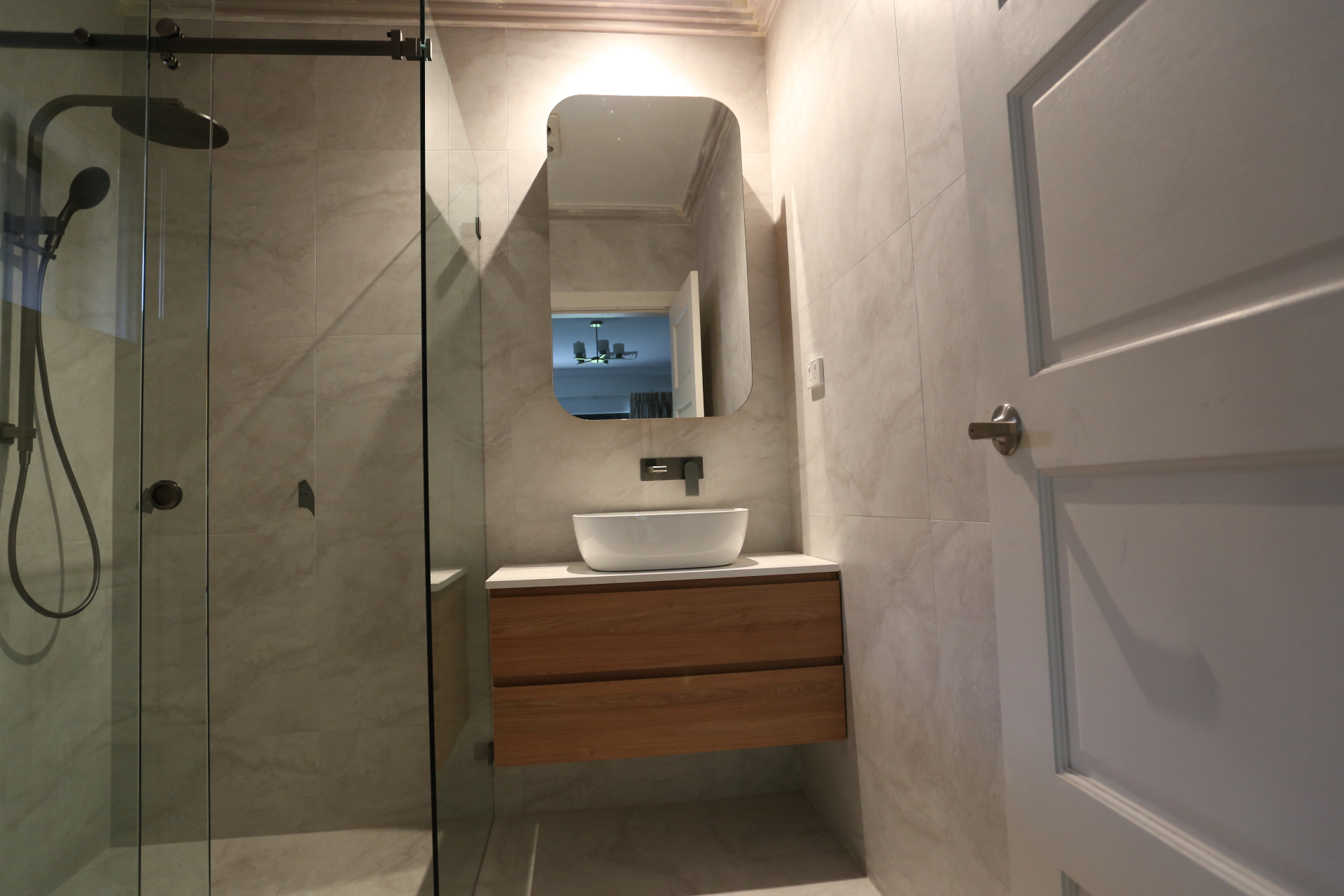 Bathroom with walnut floating vanity, vessel basin and frameless shower by Mr Woodworx