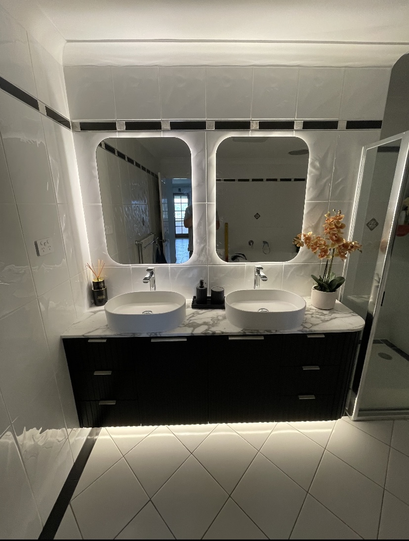Black fluted twin vanity with marble benchtop, vessel basins and backlit mirrors by Mr Woodworx