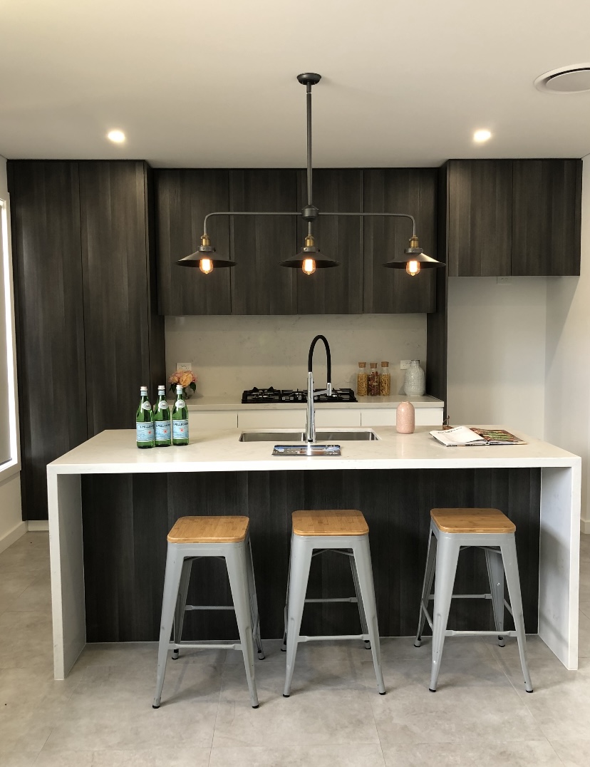 Dark timber kitchen with white waterfall island, gas cooktop and pendant lighting by Mr Woodworx