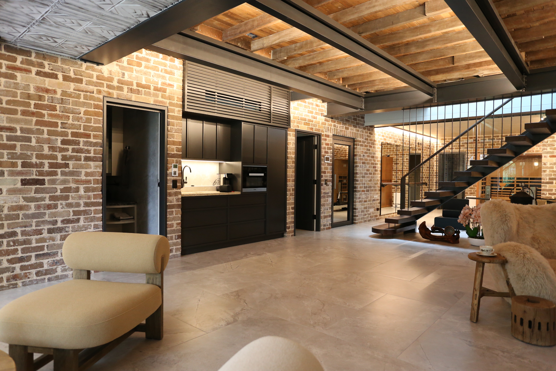 Brick loft interior with black cabinetry, steel stair and timber ceiling by Mr Woodworx