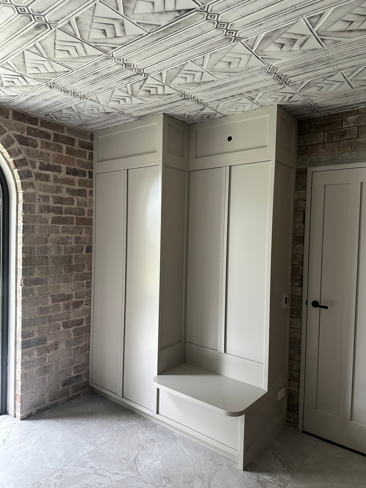 Shaker-profile mudroom cabinetry with rounded bench seat and drawer beneath a pressed-tin ceiling in Cremorne by Mr Woodworx