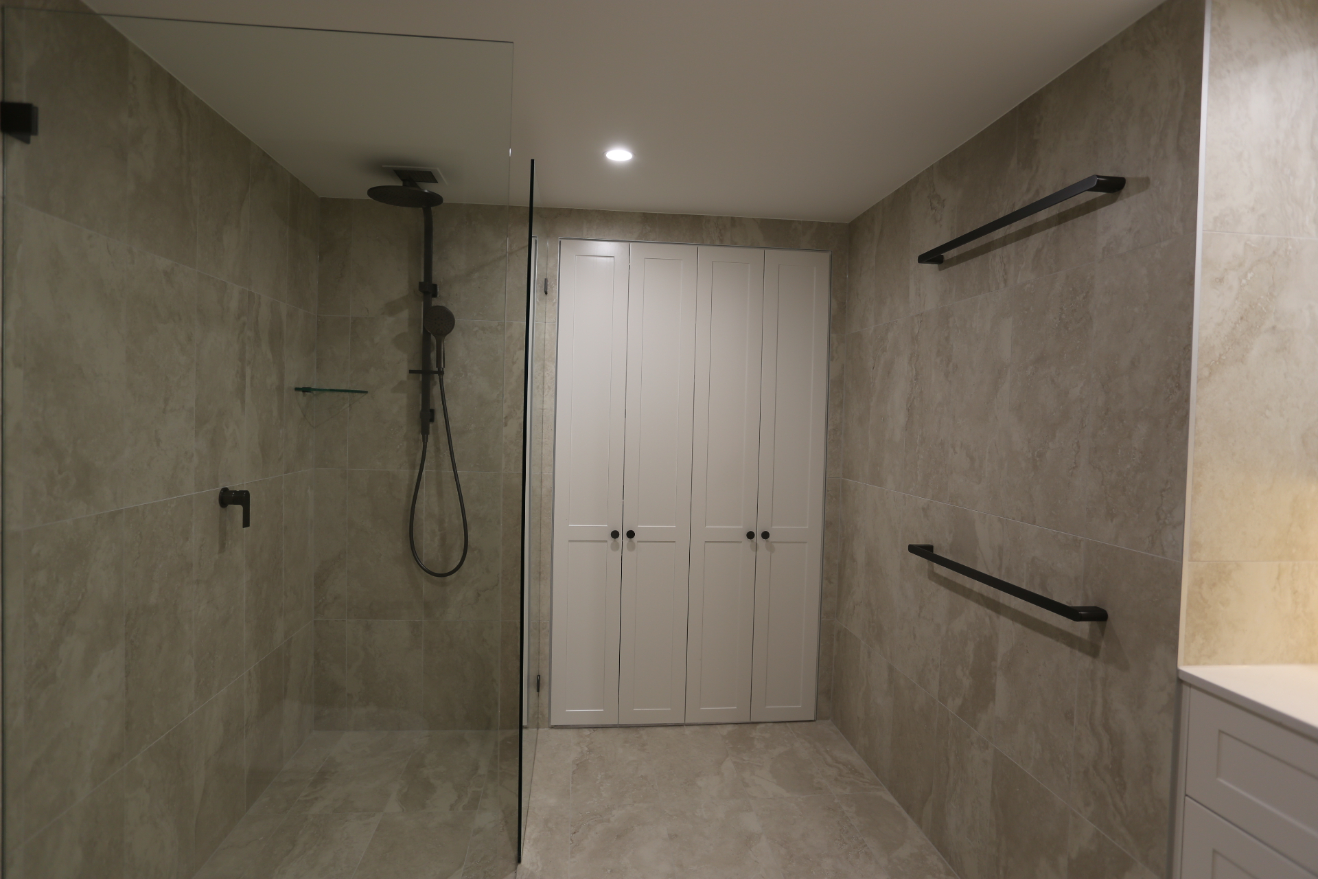 Walk-in shower renovation with large-format tiles and matte black fixtures by Mr Woodworx
