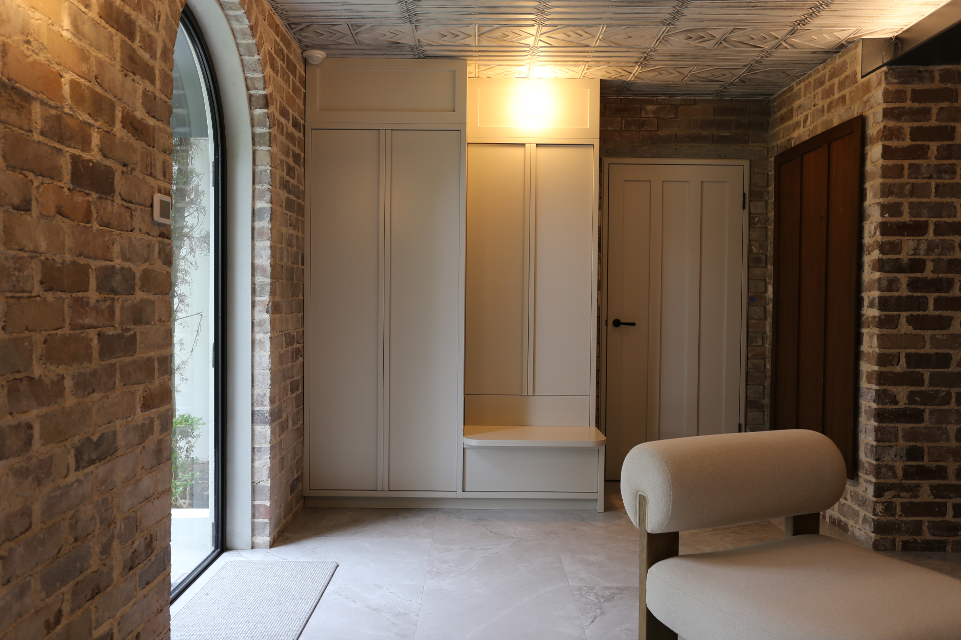 Brick mudroom entry with custom joinery and pressed-tin ceiling by Mr Woodworx